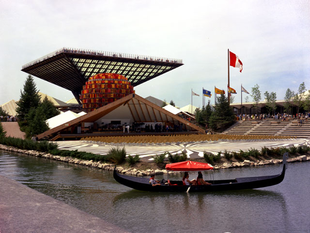 Le pavillon Katimavik du Canada, semblable à une pyramide inversée, avec, à l'avant-scène, le kiosque à musique