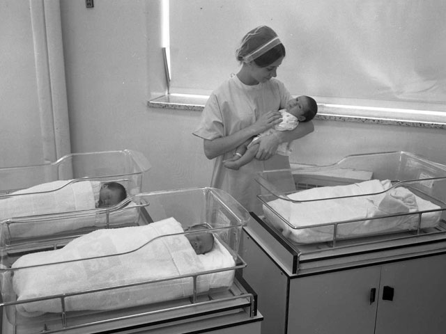 A nurse working in the nursery at Hôpital Sainte-Marie in Trois-Rivières in 1968 holds a newborn child in her arms